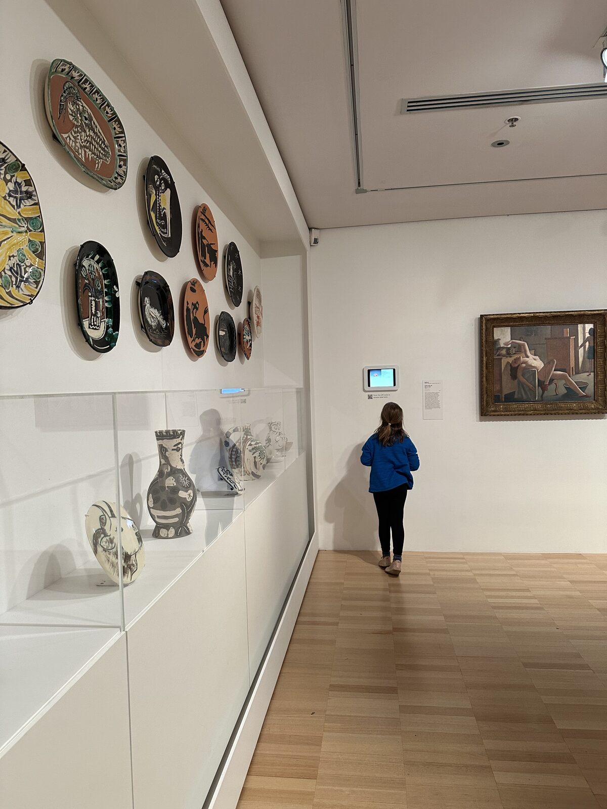 A photo of a girl looking at the information screen in the hall, next to the Picasso ceramics