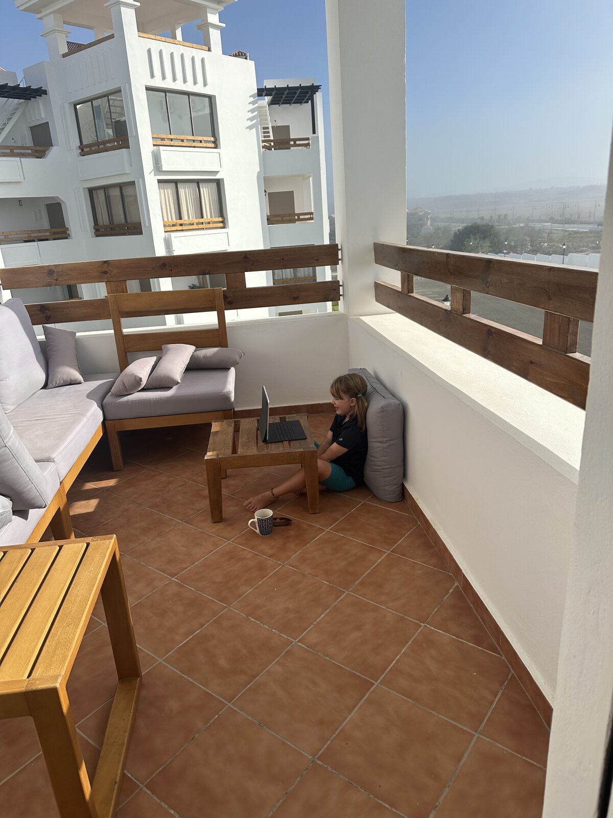 Our balcony in our 1-bed apartment in Asilah, a corner balcony being used by a girl on a zoom call